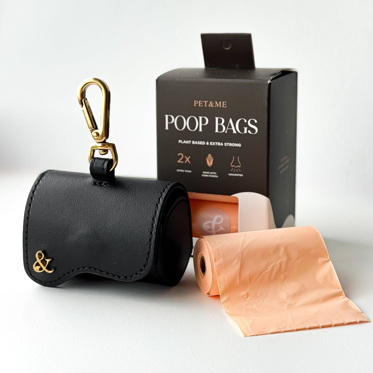 Black leather poop bag holder with gold clip next to PET & ME compostable poop bags